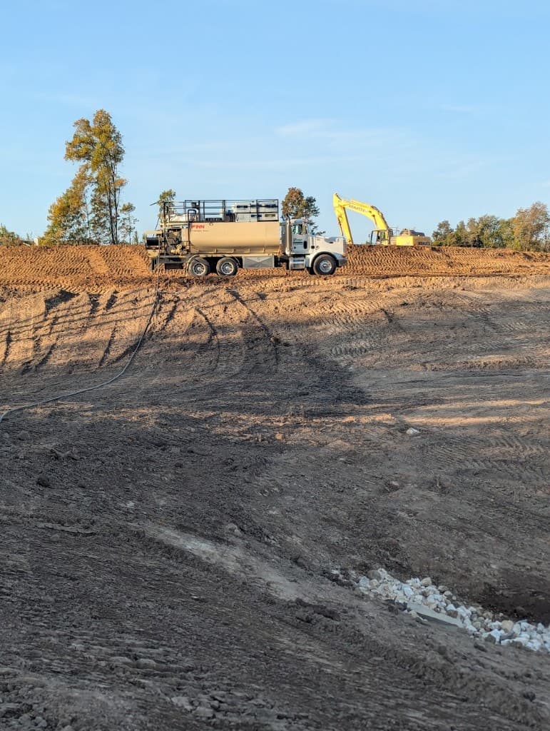 Hydroseeder truck and excavator on a construction site for erosion control