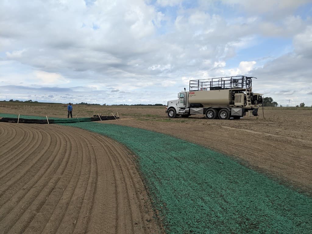 Hydroseeder truck applying hydromulch on a commercial property